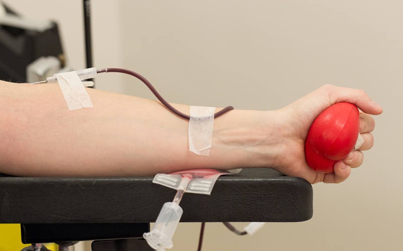 Donor in an armchair donates blood at hemotransfusion station, close-up