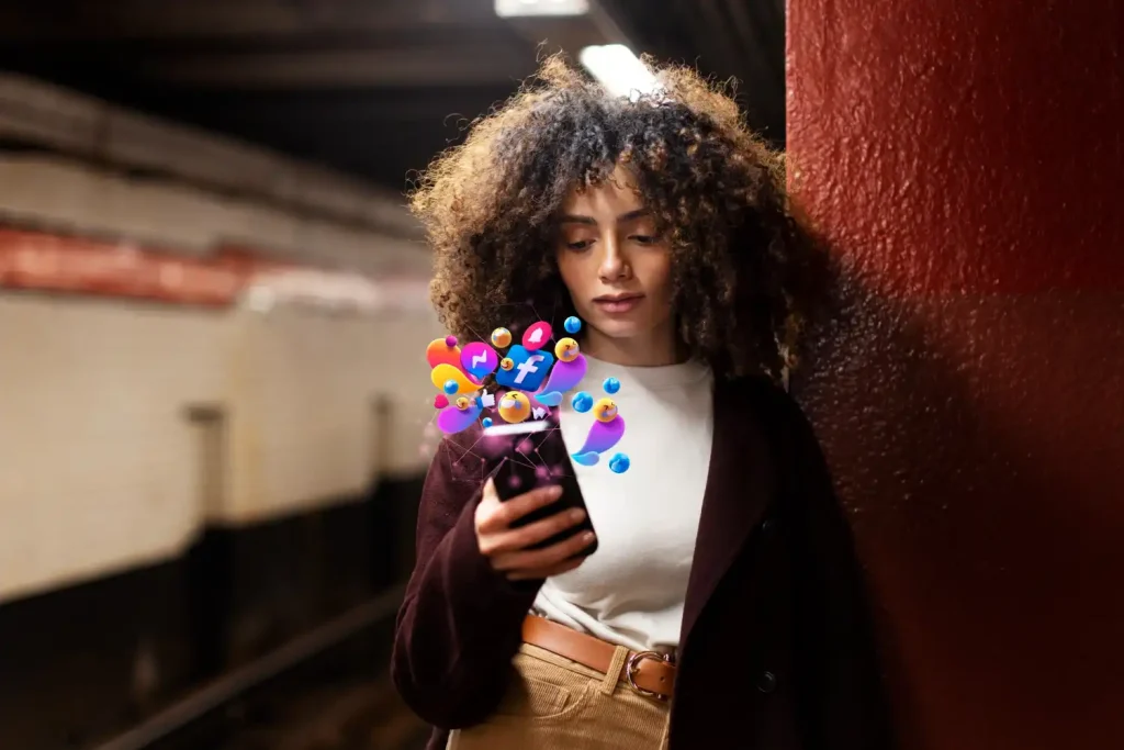 Mulher jovem com cabelo cacheado usando celular, com ícones de redes sociais e emojis representando tendências de conteúdo nas novas atualizações do Instagram