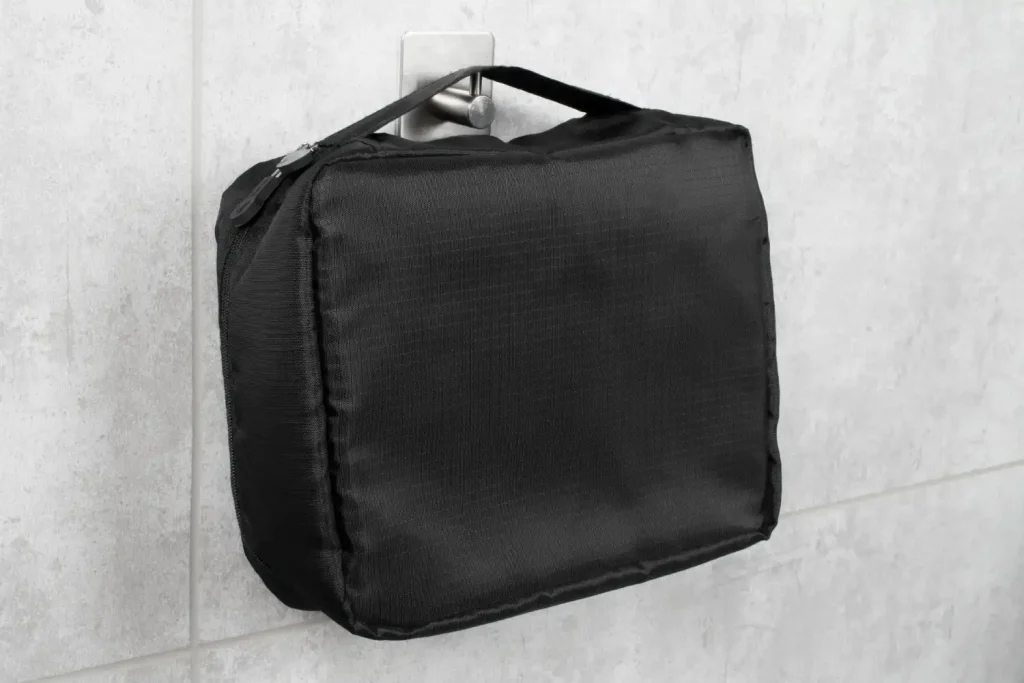 Imagem de uma bolsa térmica personalizada preta pendurada na parede, mostrando o material resistente e o design compacto.