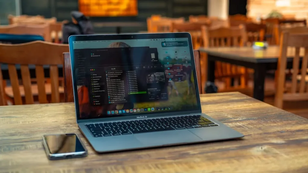 Notebook com tela exibindo código e interface de desenvolvimento de site em um ambiente de trabalho com smartphone sobre a mesa, ilustrando o que considerar antes de criar um site para sua empresa.