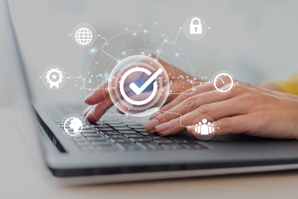 Acessibilidade Digital e LGPD: Qual a Relação Entre Inclusão e Conformidade: Mão usando laptop com interface de verificação e ícones digitais de acessibilidade e segurança, representando conformidade e inclusão online.