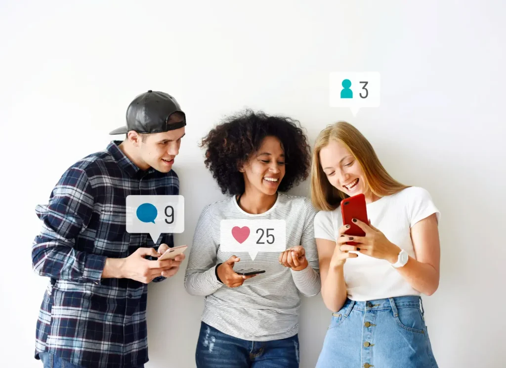 Três jovens conversam e interagem enquanto usam celular, com ícones de curtidas e comentários sobrepostos na imagem, representando Marketing de Comunidade: Como Construir Audiências Fiéis Fora dos Algoritmos.