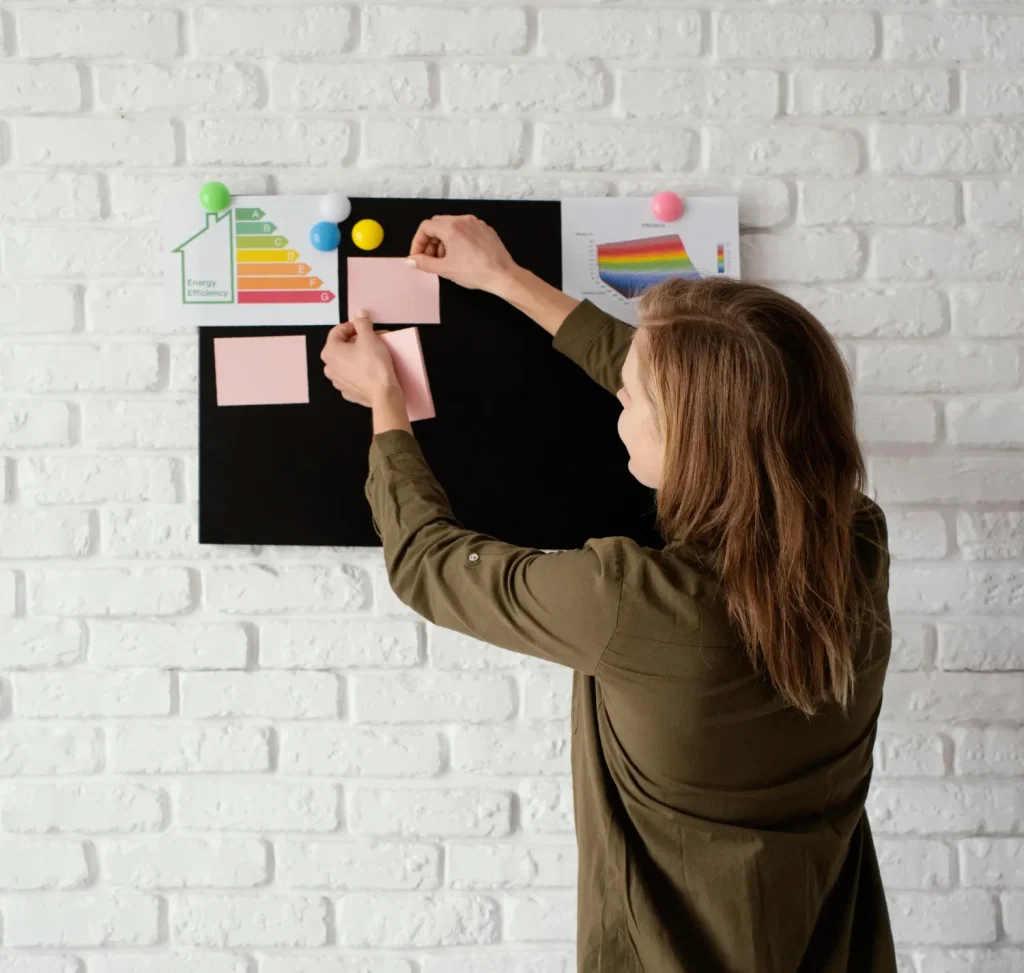 Experiência sensorial como Métrica de Branding: Como medir o que uma ativação “Faz Sentir: Pessoa montando painel visual com gráficos e paleta de cores ao lado de uma parede de tijolos brancos, compondo um material para avaliação de experiência e branding.