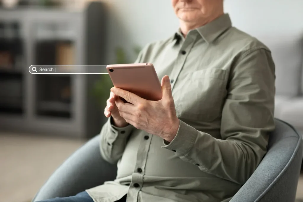 GEO na Prática: Como Adaptar Conteúdo Para Ser Citado por IA Generativa, Não Só Rankeado no Google: Homem sentado em um sofá usando um tablet em ambiente interno, com foco em tecnologia e busca online; imagem transmite adaptação de conteúdo para ser citado por IA generativa.