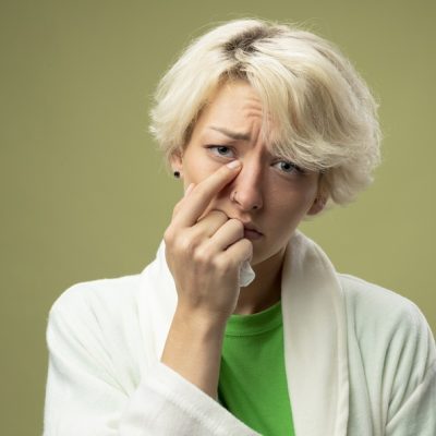 sick unhealthy woman with short hair feeling unwell pointing with finger at her nose being unhappy standing over light background - Fonte: Freepik