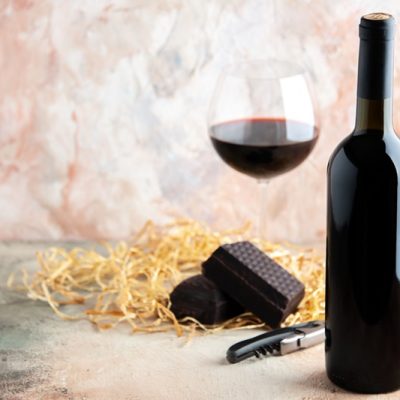 front view glass of wine with bottle and chocolate on light background alcohol lemonade holiday bar champagne juice drink