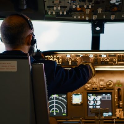 Male airline captain fixing altitude and longitude buttons, using dashboard navigation command and control panel. Flying airplane with aircrew and radar compass, power engine and windscreen. Créditos: Freepik