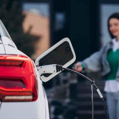 Woman charging her electric car with charging pistol