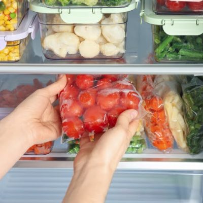 Woman taking plastic bag with frozen tomatoes from - Créditos: istock/Liudmila Chernetskarefrigerator, closeup