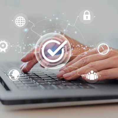 Acessibilidade Digital e LGPD: Qual a Relação Entre Inclusão e Conformidade: Mão usando laptop com interface de verificação e ícones digitais de acessibilidade e segurança, representando conformidade e inclusão online.