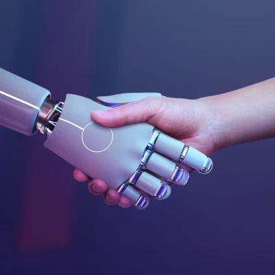 Dois braços estendidos em um aperto de mão entre humano e um braço robótico, com destaque para a tecnologia e a colaboração; visão de como a Inteligência Artificial está transformando pequenas empresas brasileiras em 2026.