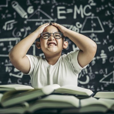Boys with glasses write books and think in the classroom