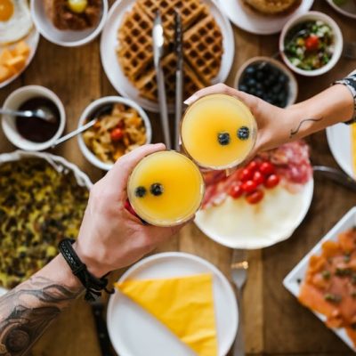 Close up of hands of Young mixed race couple cheering with cocktail glasses during brunch at home. Both dressed in casual clothes. Interior of private residence in Toronto, Canada. (Créditos: FOTOGRAFIA INC. / iStock)