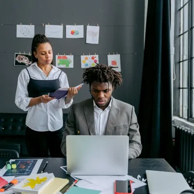 Equipe de planejamento de evento corporativo analisando ideias em escritório bem iluminado com parede de fotos e documentos compartilhados