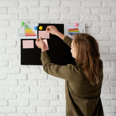 Experiência sensorial como Métrica de Branding: Como medir o que uma ativação “Faz Sentir: Pessoa montando painel visual com gráficos e paleta de cores ao lado de uma parede de tijolos brancos, compondo um material para avaliação de experiência e branding.