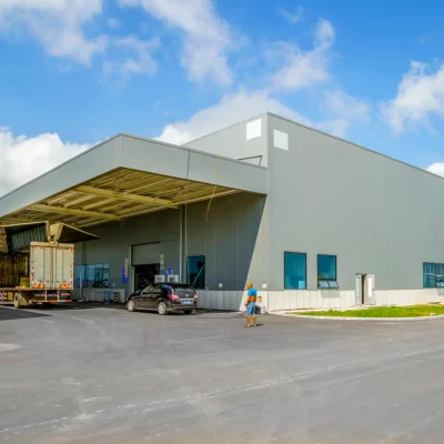 Imagem de um galpão industrial moderno, com caminhões e veículos estacionados na frente, destacando os benefícios do aluguel de galpão para empresas.