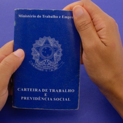 Brazil Work Card. Translation - Federative Republic of Brazil, Ministry of Labor. Hand holding the Brazil Work Card. Labor document FGTS, INSS, unemployment, salary, CTPS and CLT.