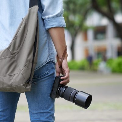 Rear view of photographer with bag and digital camera