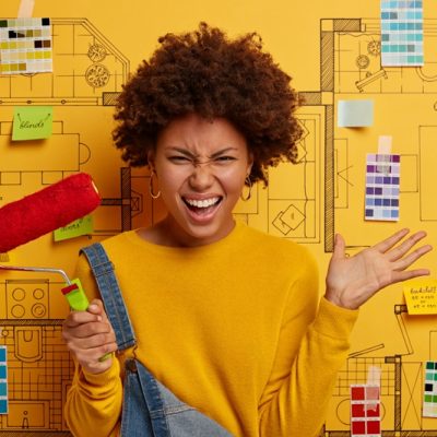 Annoyed woman with curly Afro hairstyle, raises palm, holds paint roller, refurbishes walls, dressed casually, stands against house design project, improves room condition, has home improvement - Freepik