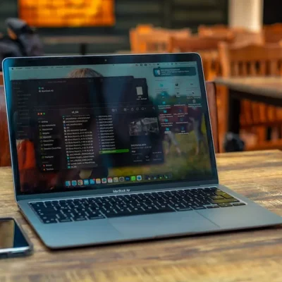 Notebook com tela exibindo código e interface de desenvolvimento de site em um ambiente de trabalho com smartphone sobre a mesa, ilustrando o que considerar antes de criar um site para sua empresa.