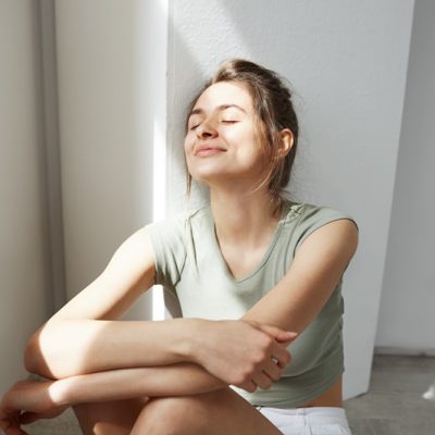 Portrait of tender young beautiful girl smiling with closed eyes enjoying morning sunlights sitting on floor over white wall. Copy space. Imagem ilustrativa
Freepik