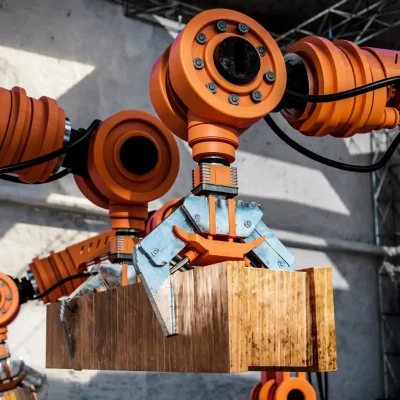 Robôs industriais trabalhando na montagem de uma caixa de madeira, destacando a importância da manutenção para prolongar a vida útil de máquinas industriais e reduzir custos operacionais.