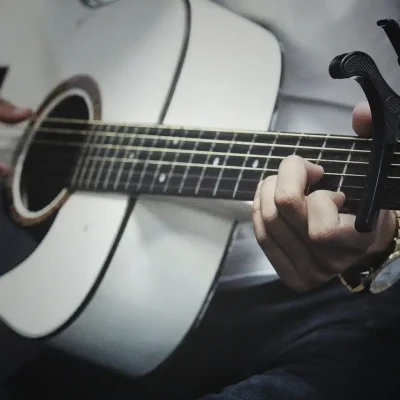Pessoa tocando violão, uma atividade que ajuda a reduzir o estresse ao envolver a mente e as emoções na música.
